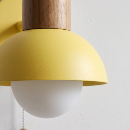 Close-up of the wood knob, matte yellow dome and opal glass globe on the Nordic macaron wall sconce