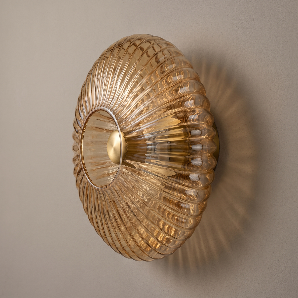 Nordic vintage cognac striped glass round disc wall sconce with brass fitting, lamp off, mounted on a plain greige plaster wall