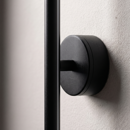 Close-up of the round black mount disc and matte aluminum bar of the minimalist strip LED wall sconce