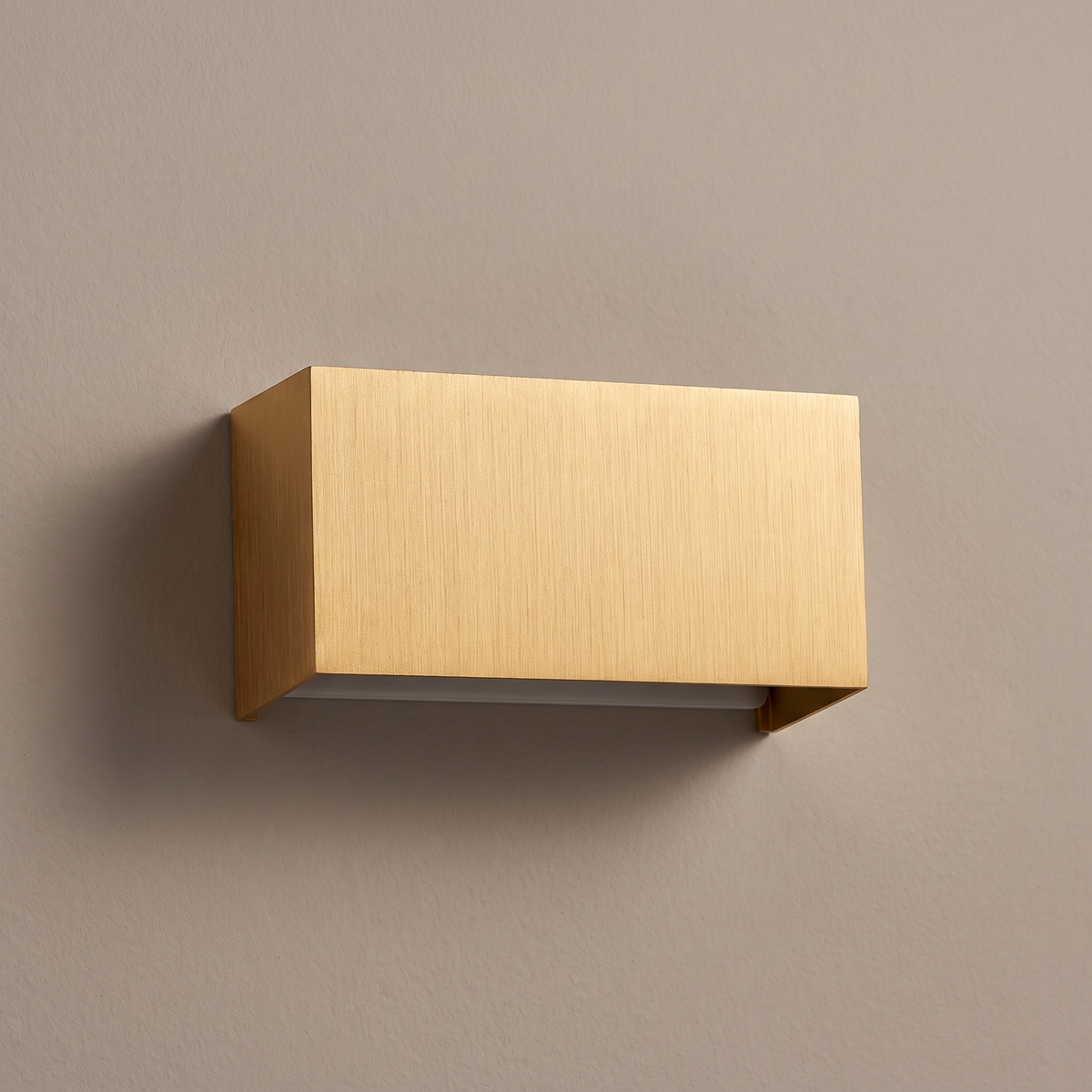 Modern minimalist brushed gold aluminum rectangular LED wall sconce mounted on a plain greige wall, light off, front view