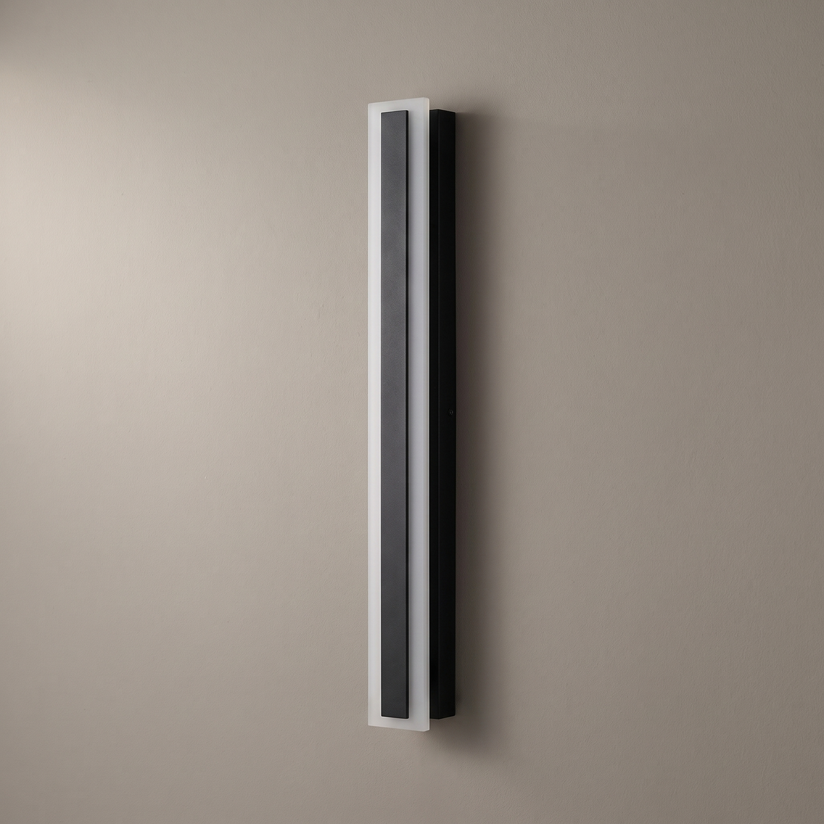 Minimalist elongated bar black acrylic LED outdoor wall light mounted vertically on a plain greige wall, light off, front view
