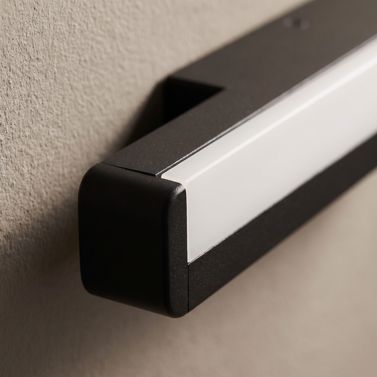 Close-up of the matte black frame and frosted acrylic diffuser end cap of the elongated bar outdoor waterproof wall light