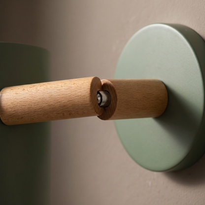 Close-up of the natural beech wood pivot arm and sage green backplate of the Nordic macaron rotatable cylinder wall sconce