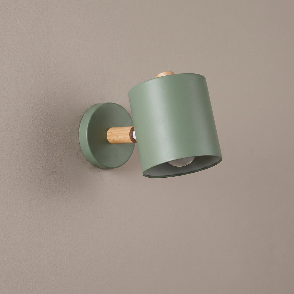 Nordic macaron sage green metal cylinder wall sconce with wood pivot arm and round backplate on a plain greige wall, light off