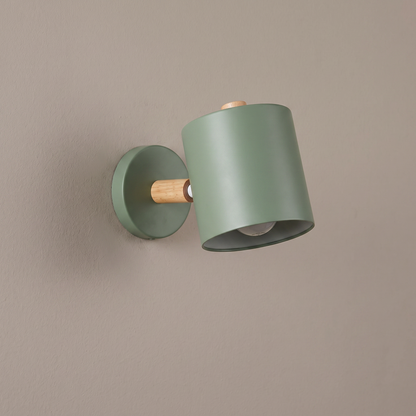 Nordic macaron sage green metal cylinder wall sconce with wood pivot arm and round backplate on a plain greige wall, light off