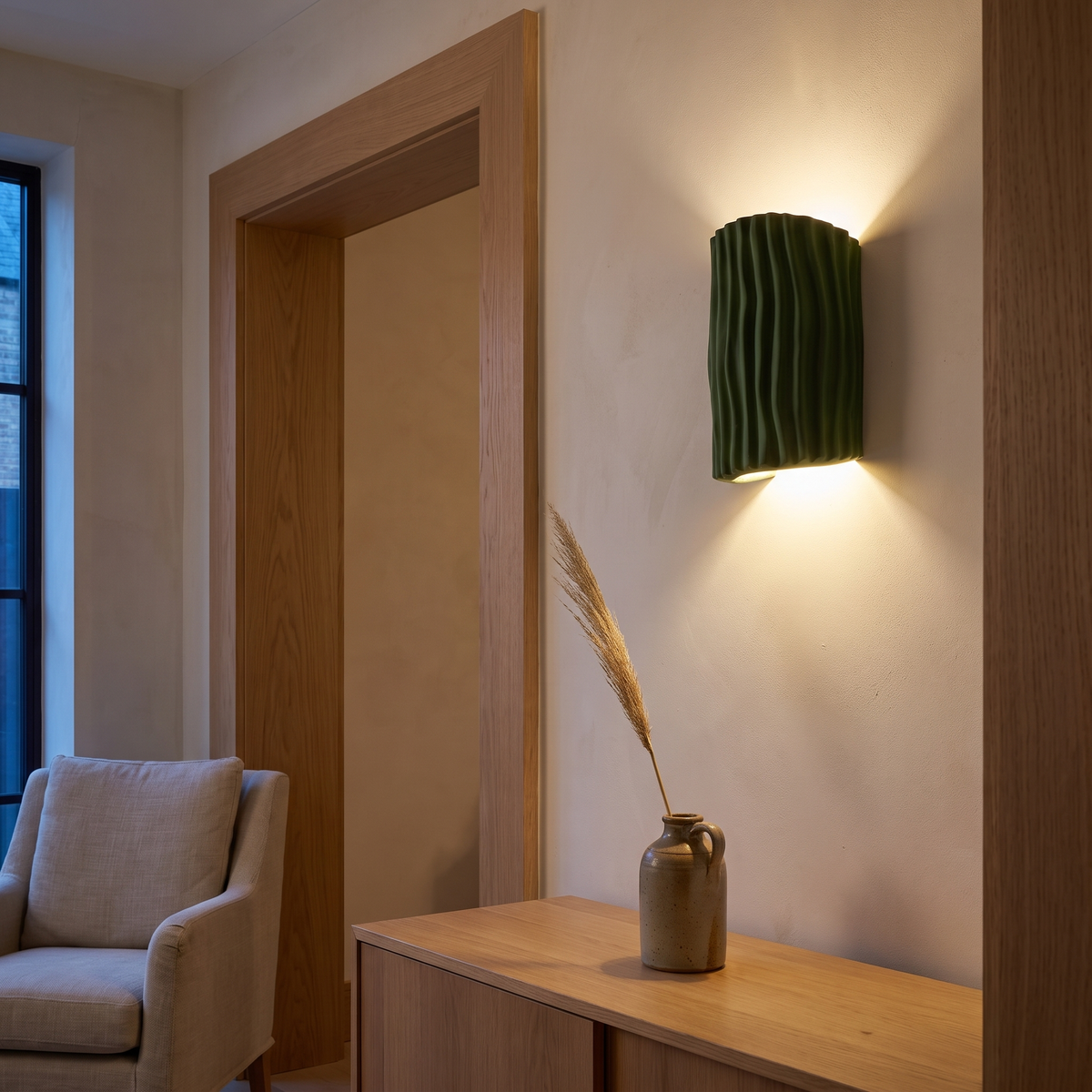 Nordic green resin striped wall sconce lit at dusk beside a doorway above an oak sideboard in a living room