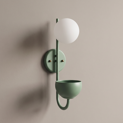 Green iron sphere planter wall sconce with opal white glass globe and storage bowl on a plain greige wall, lamp off