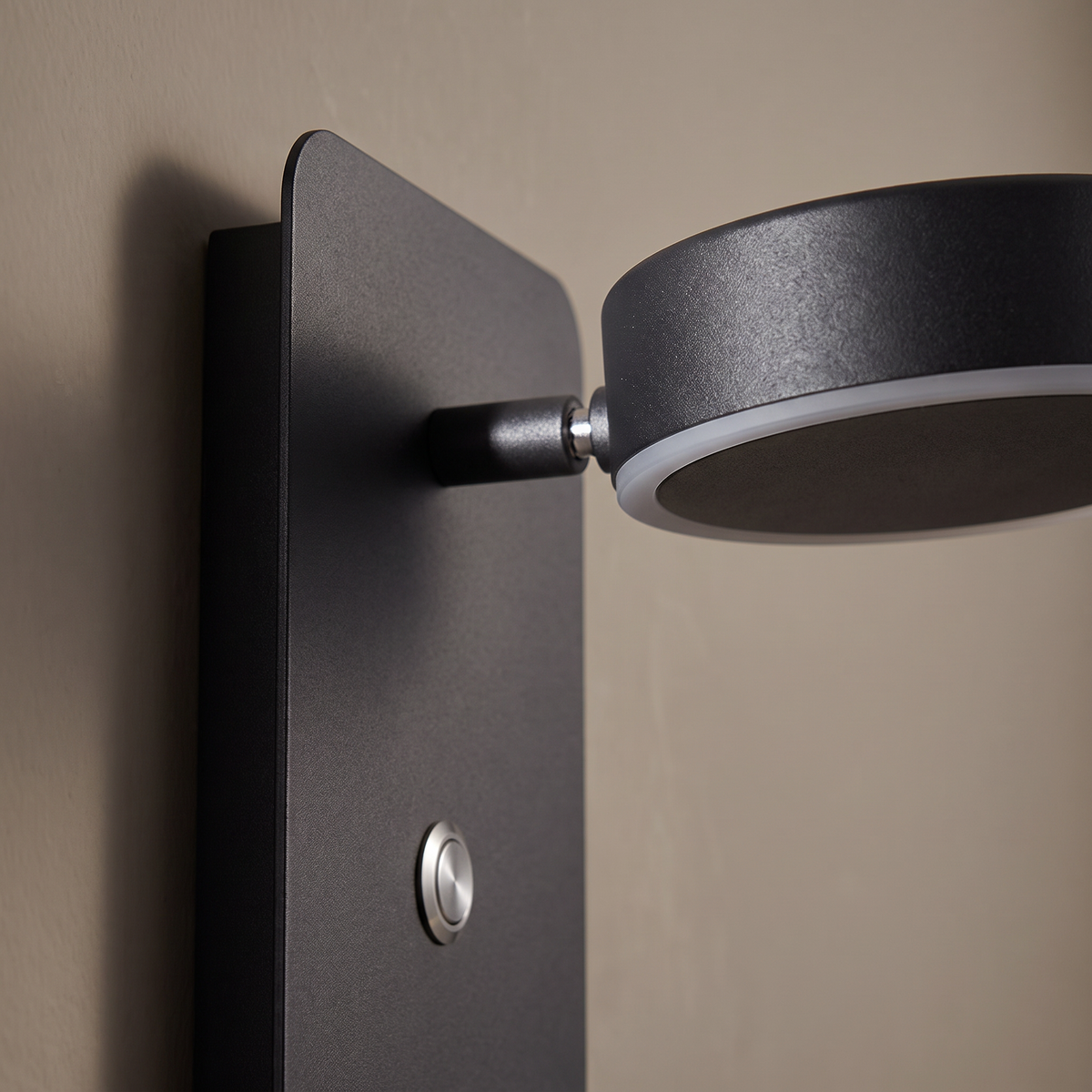 Close-up of the matte black iron pivoting LED spotlight head and push switch on the modern square wall sconce