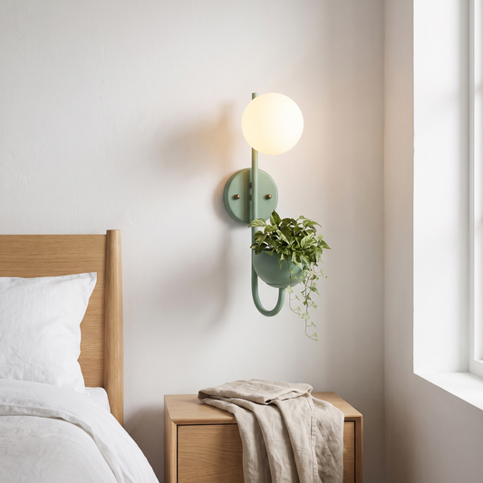 Green iron sphere planter wall sconce with opal glass globe glowing warm beside a light oak bed
