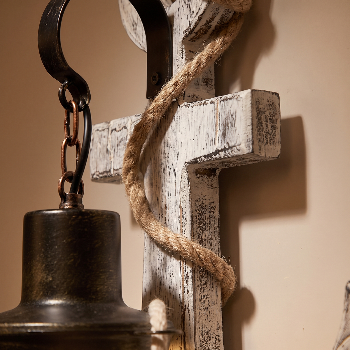 Close-up of sisal rope wrapped around the distressed white wood anchor and black iron hook of the nautical wall sconce