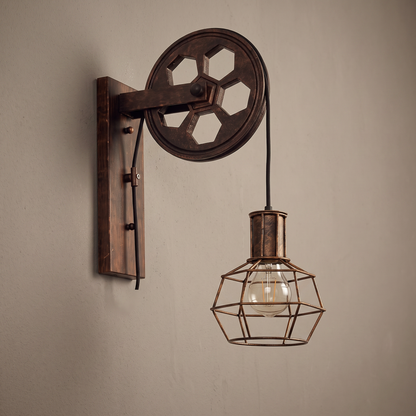 Vintage pulley iron and wood wall sconce lamp with wire cage shade on a plain greige wall, lamp off