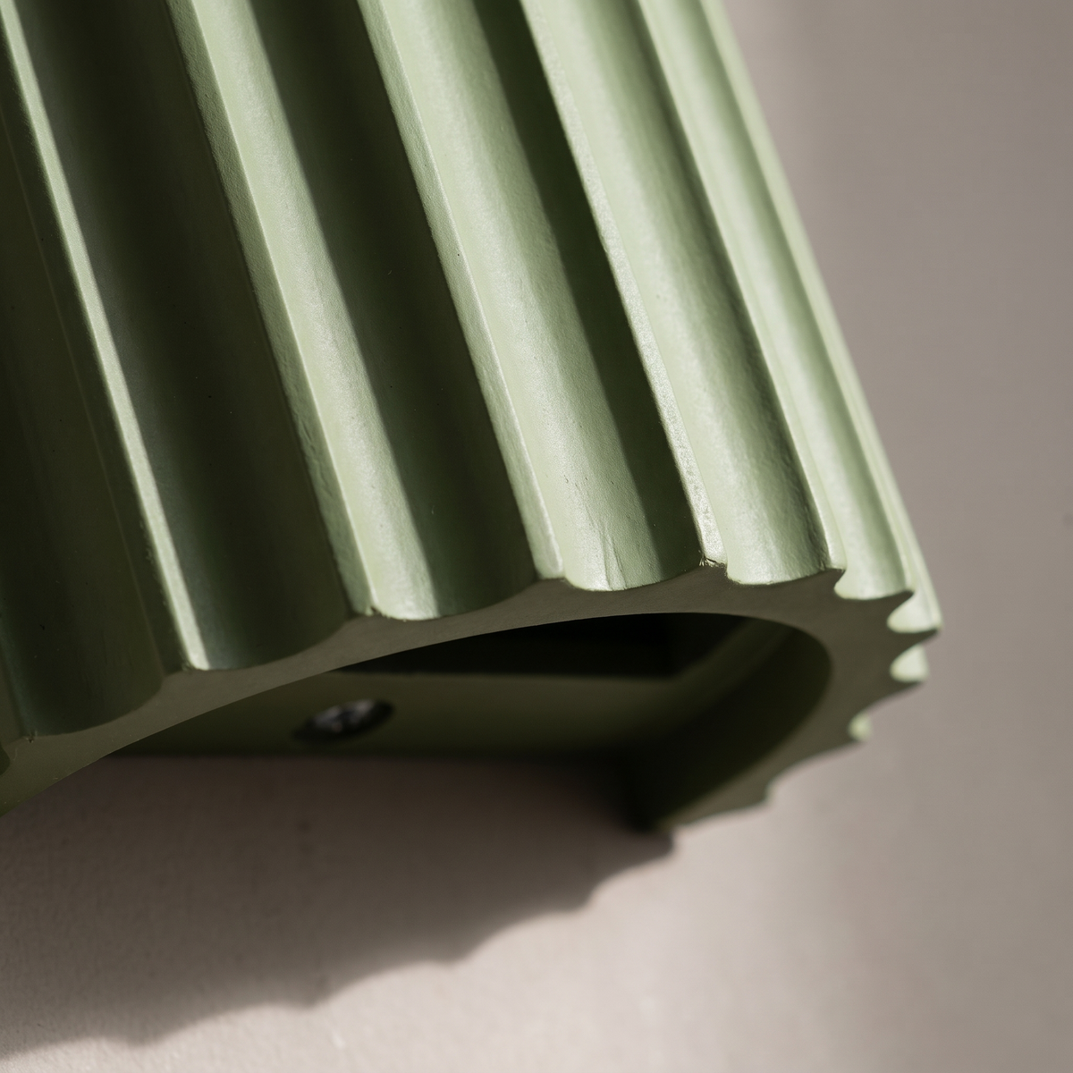 Close-up of the vertical fluted ribs and matte finish of the sage green resin half cylinder wall sconce