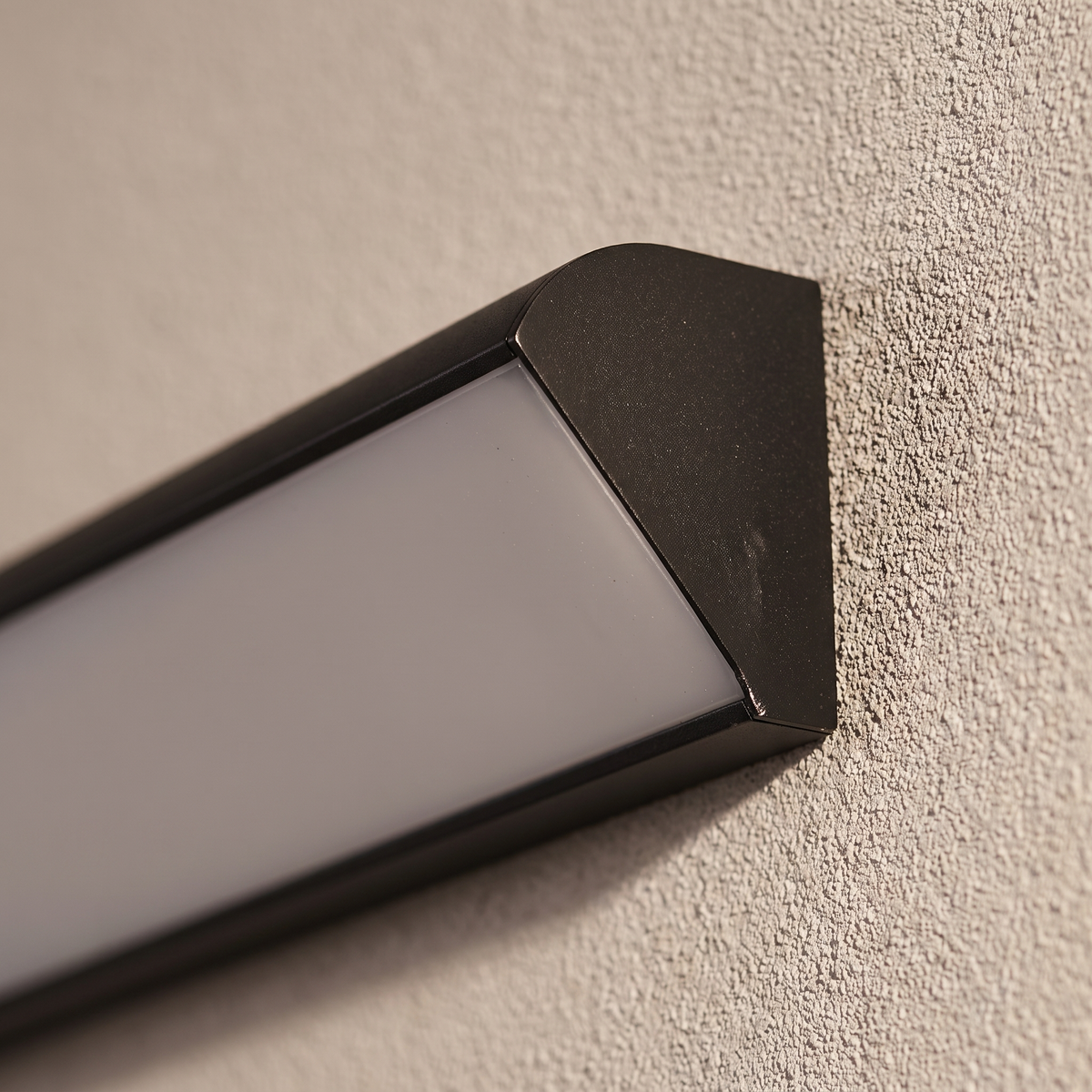 Close-up of the black powder-coated aluminum end cap and frosted acrylic diffuser seam of the waterproof linear wall light