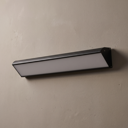 Black aluminum linear wedge-profile LED wall light with frosted acrylic diffuser on a plain greige wall, lamp off
