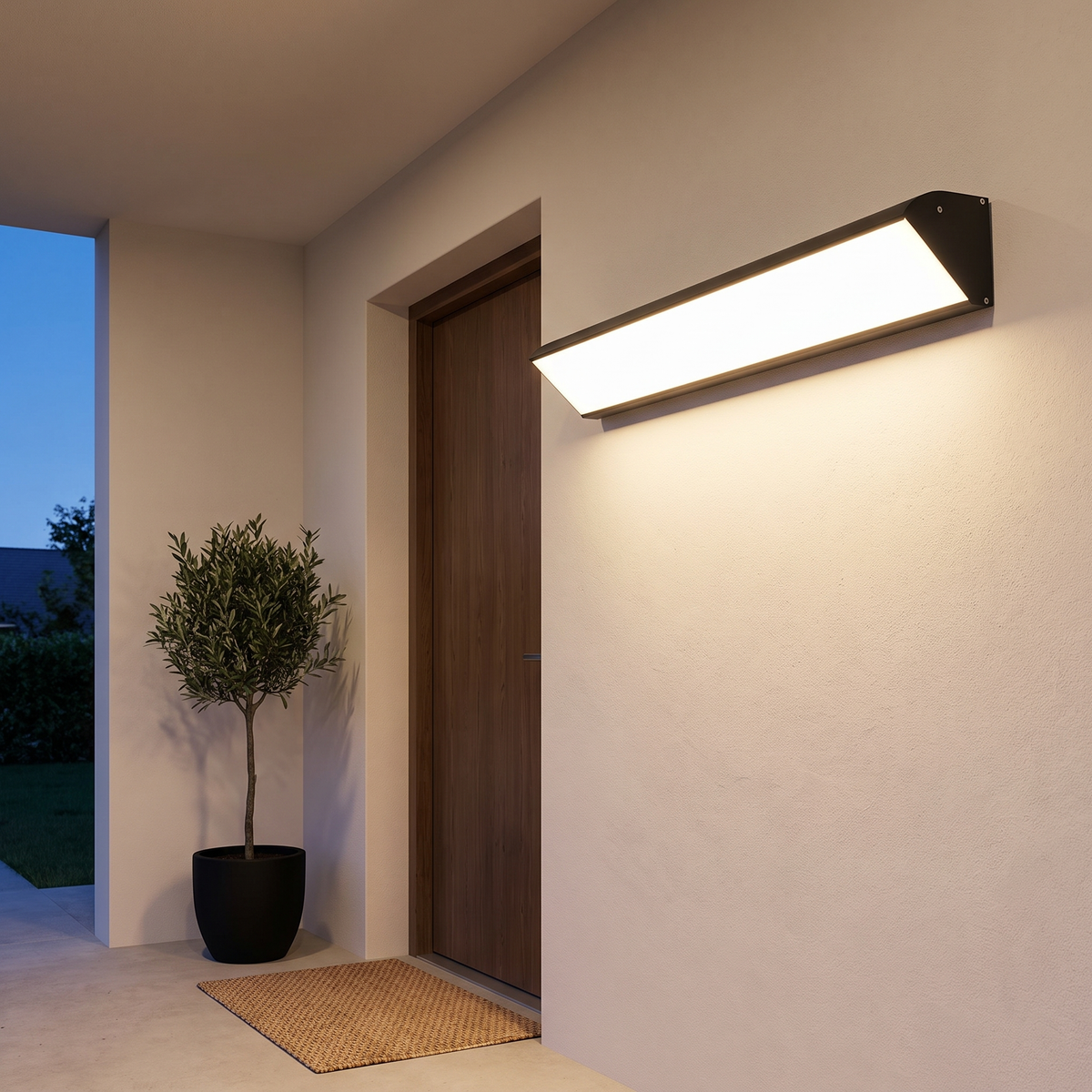 Black long LED outdoor wall sconce lit in the evening beside a dark oak front door on a covered entry porch